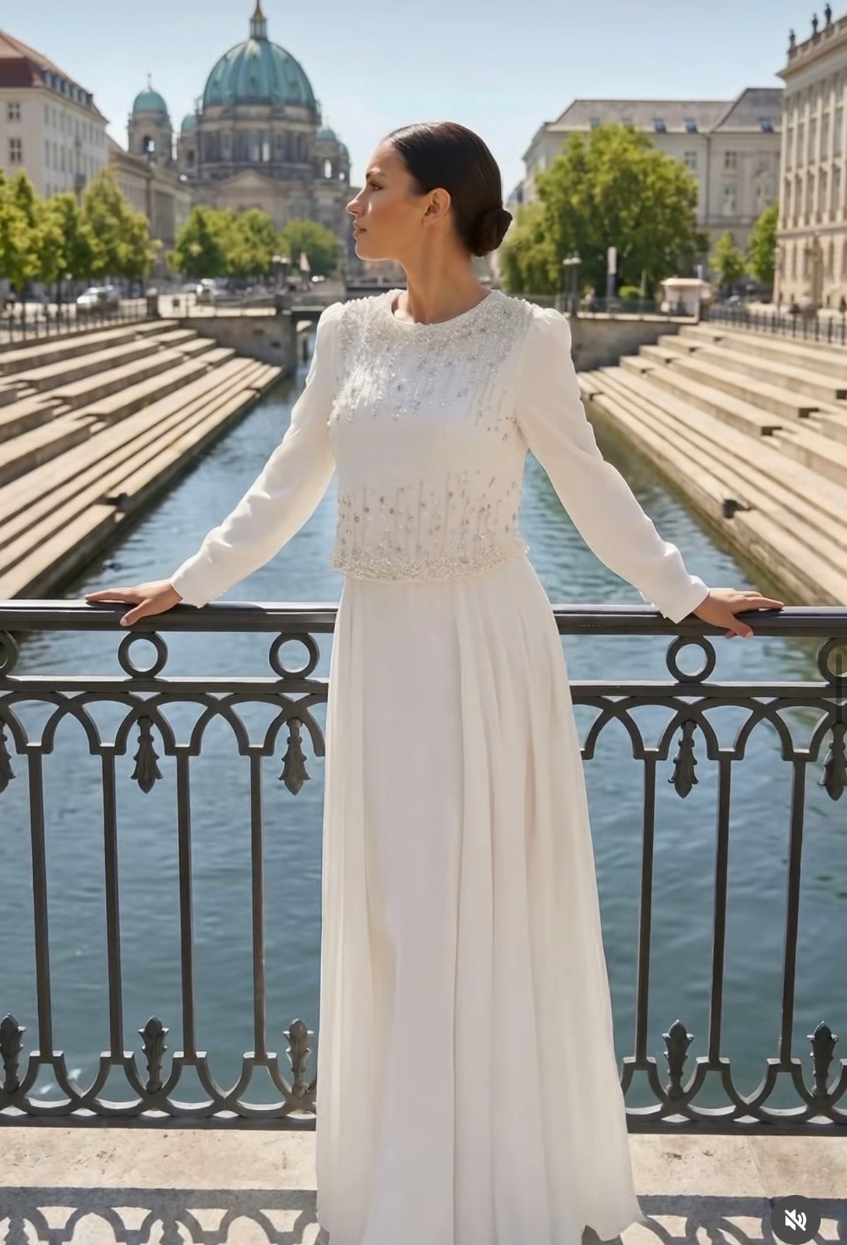 White modest bridal dress with pearl and crystal embellished bodice, long sleeves, and flowing pleated skirt