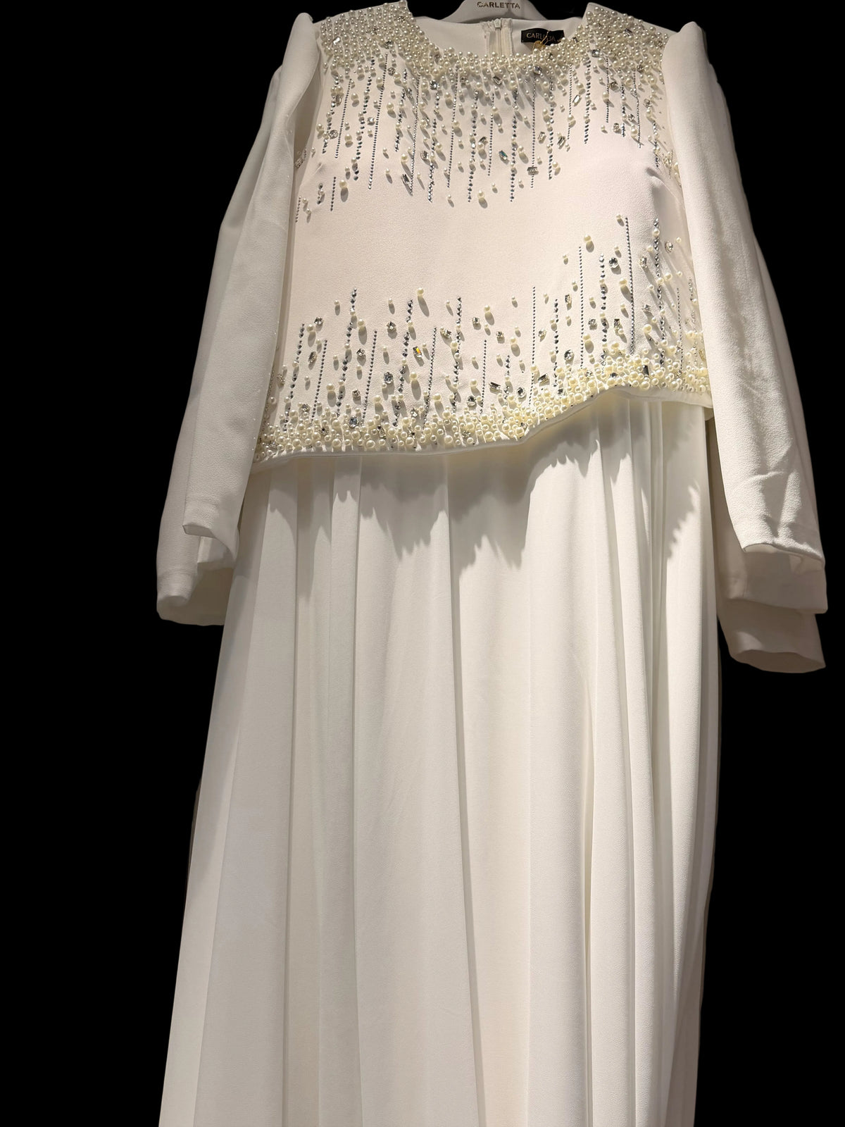 White pearl and crystal embellished modest bridal dress on hanger